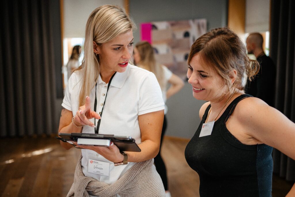 Vanessa zeigt einer Teilnehmerin etwas auf dem iPad und erklärt den personalisierten Plan