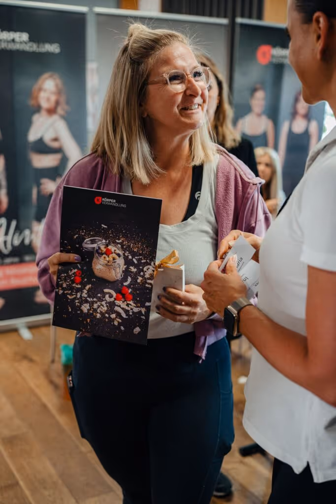 Frau hält das Körperverwandlung-Kochbuch in der Hand und lächelt – gesunde Ernährung leicht gemacht dank Meal Prep Rezepten und Begleitung im Coaching