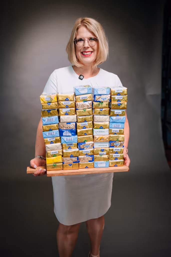 Bild einer Frau namens Stephanie, die 15 Kilo abgenommen hat. Sie trägt ihr abgenommenes Gewicht in Form von Butter. Inspirierende Geschichte über Abnehmen und mehr Lebensfreude