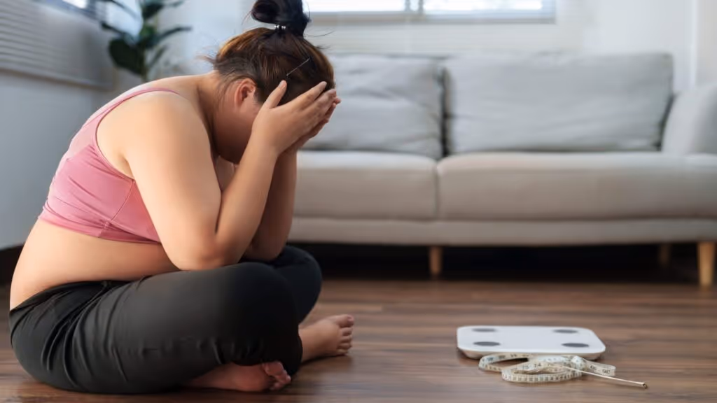 Frau schaut enttäuscht auf die Waage, weil Abnehmen trotz Wechseljahre nicht funktioniert – Frust über stagniertes Gewicht trotz Anstrengung