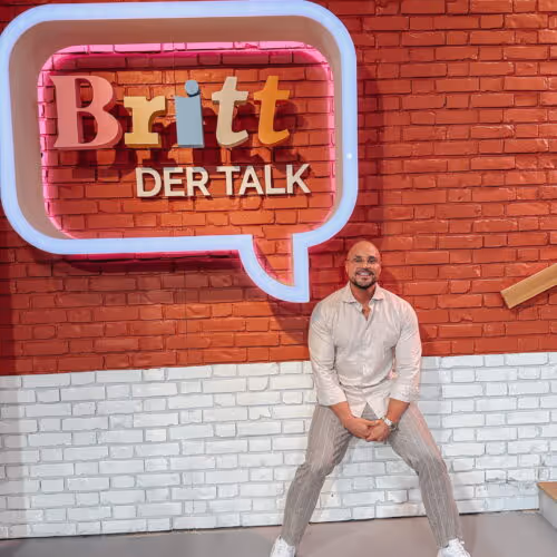 Andreas Kotte, Ernährungsberater aus Köln steht lächelnd vor dem Britt der Talk Neonschild das als Sprechblase geformt ist