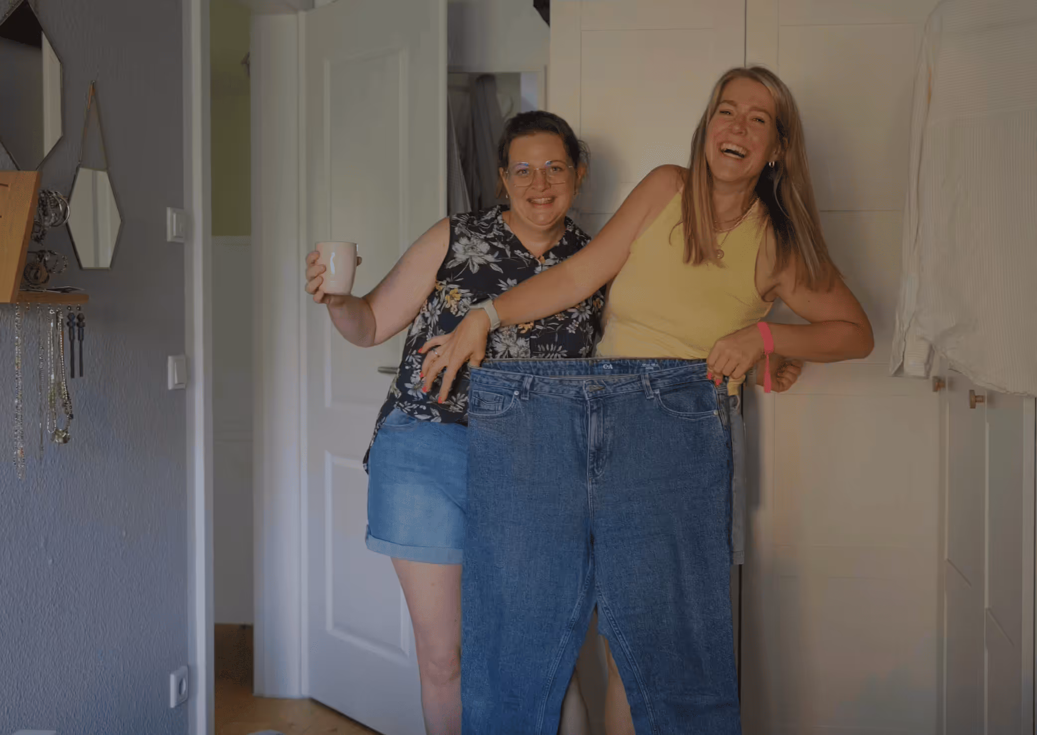 Zwei Frauen zeigen stolz eine zu große Jeans nach einer erfolgreichen und nachhaltigen Gewichtsabnahme ohne Jojo Effekt. Symbol für dauerhafte Veränderung, Wohlfühlen und neue Leichtigkeit.