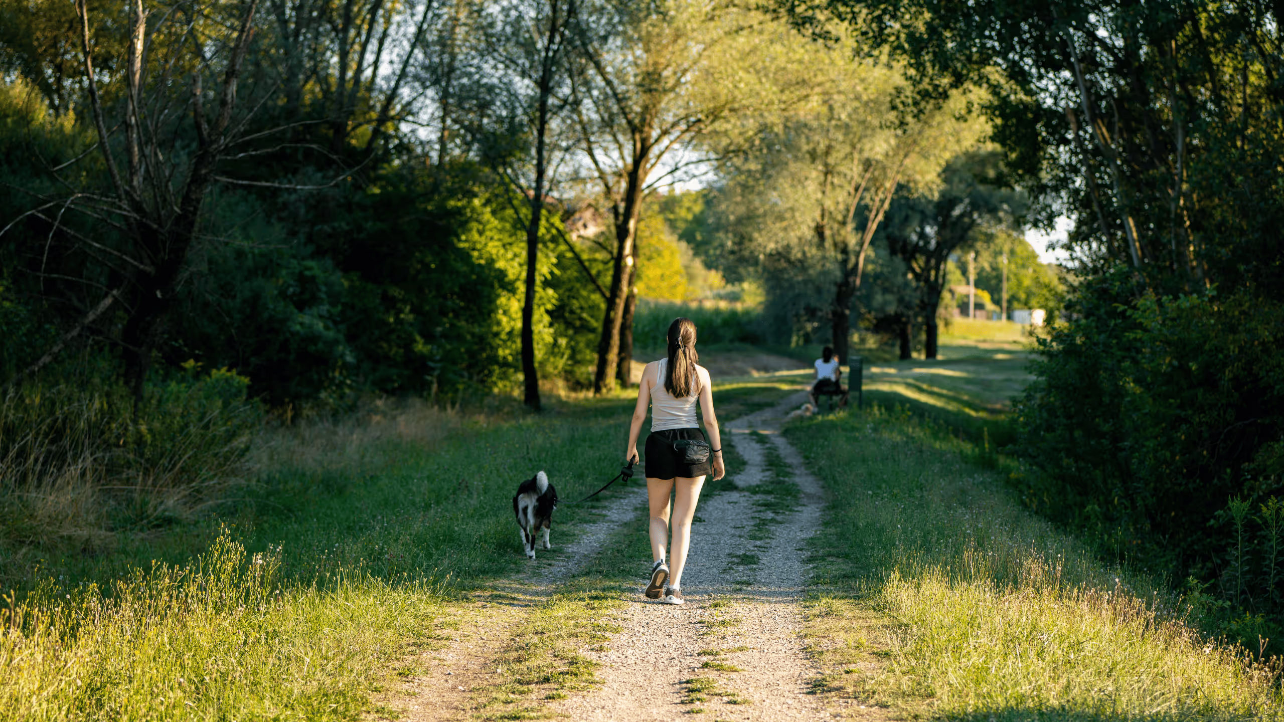 Frau geht entspannt mit ihrem Hund durch die Natur, symbolisiert alltagstaugliche Bewegung für gesundes Abnehmen ohne Druck und ohne Jojo Effekt.