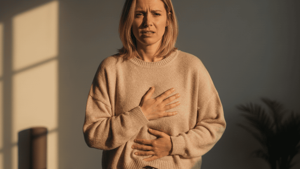 Frau hält sich Brust und Bauch wegen hormoneller Beschwerden – zeigt mögliche Auswirkungen von Pille oder Hormonspirale auf das Wohlbefinden.