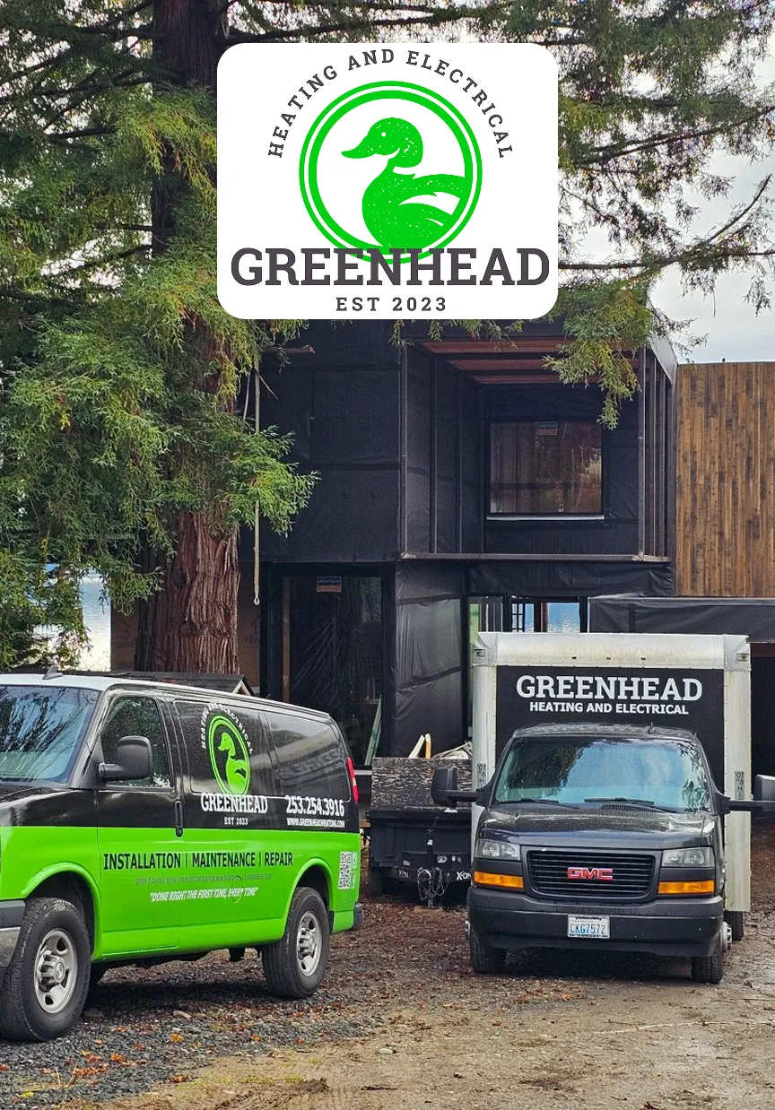 Greenhead Heating and Electrical vehicles parked in front of a modern construction site, showcasing service offerings.
