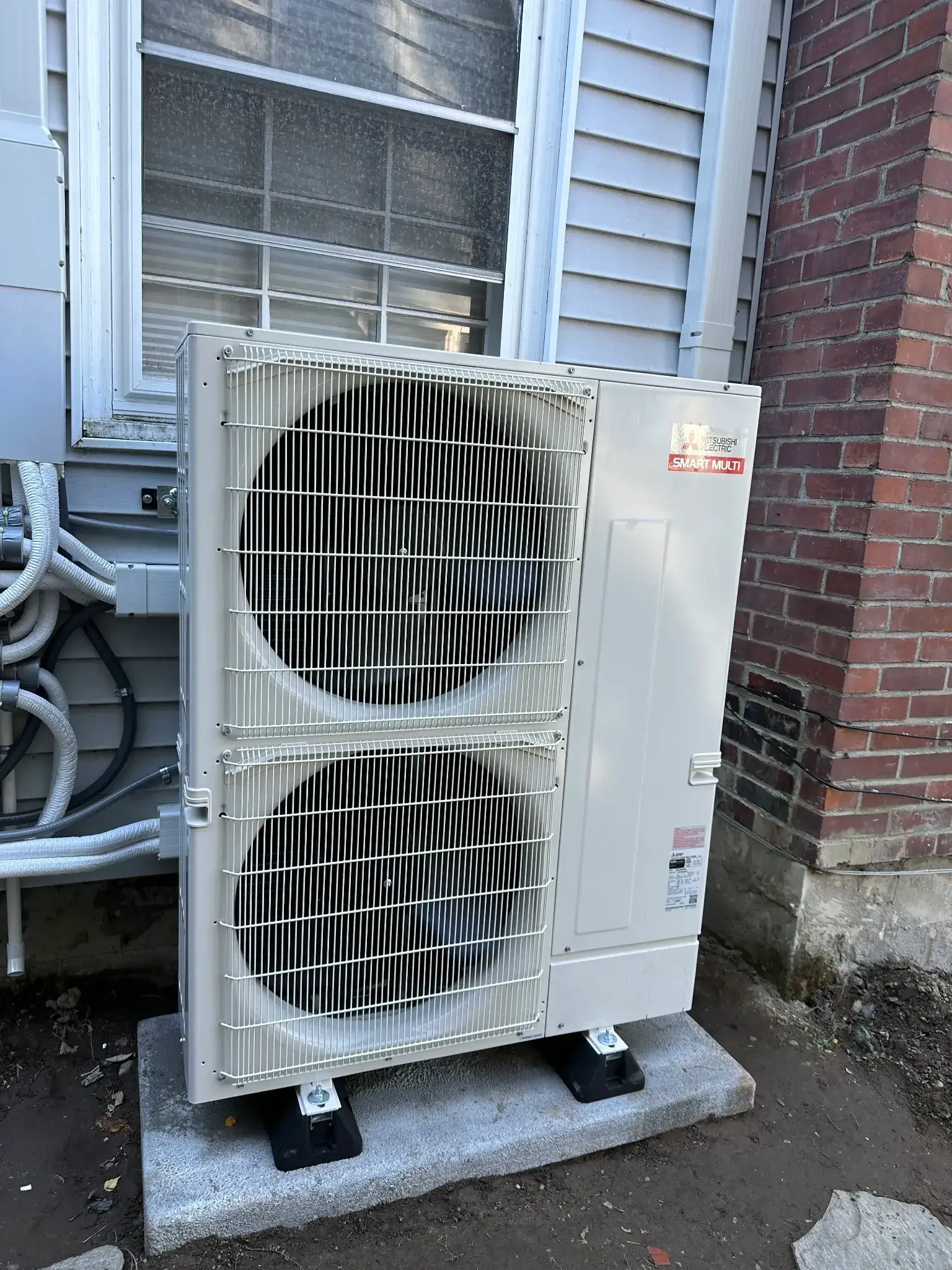 Outdoor air conditioning unit installed next to a house, showcasing energy-efficient cooling technology.
