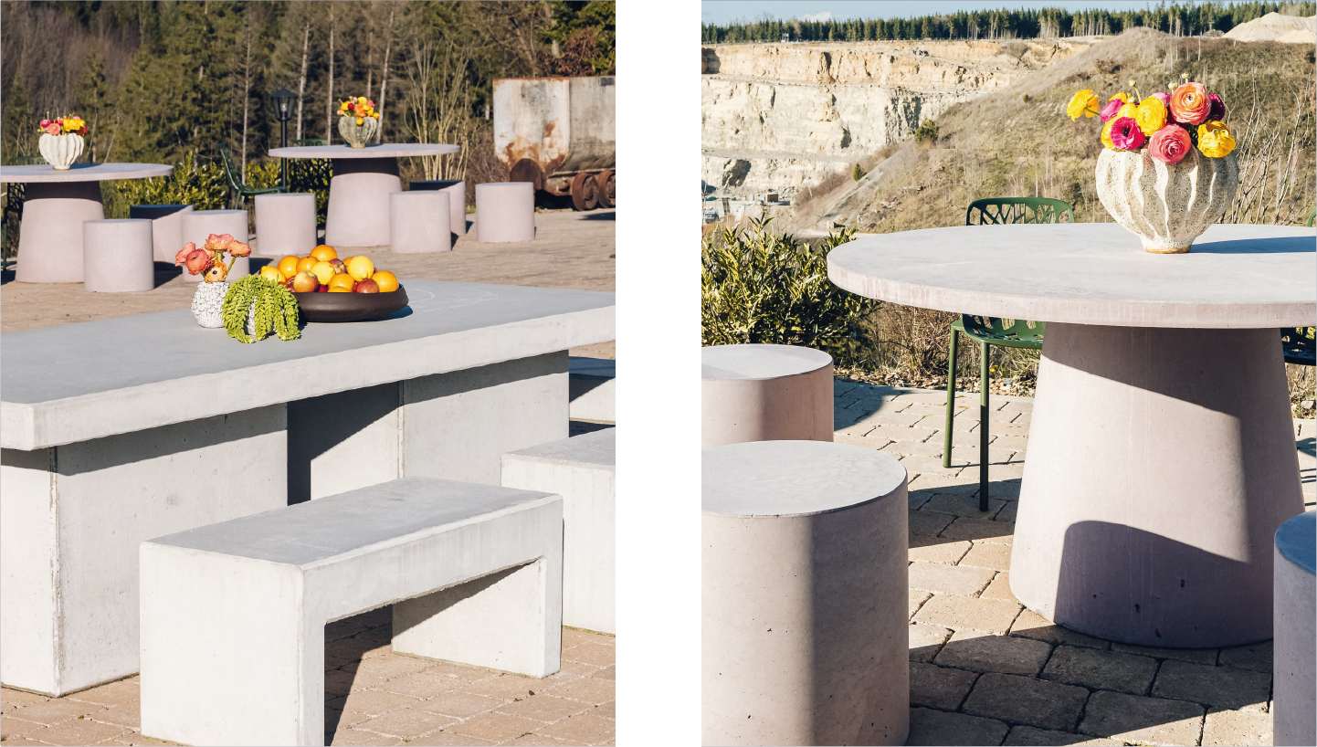 Outdoor concrete tables and stools with colorful flower vases and a bowl of fruits on a patio.