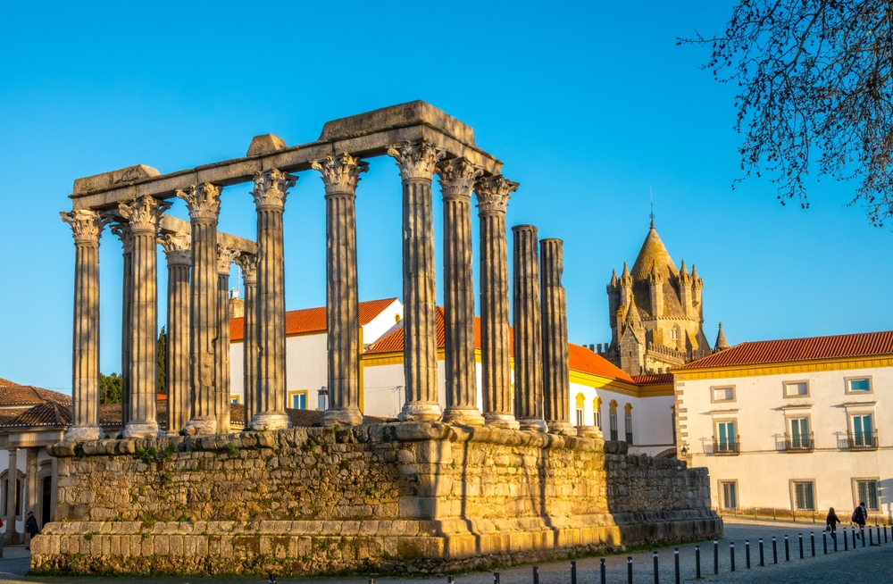 Ancient Roman temple ruins with tall stone columns stand in a Alentejo square in Portugal
