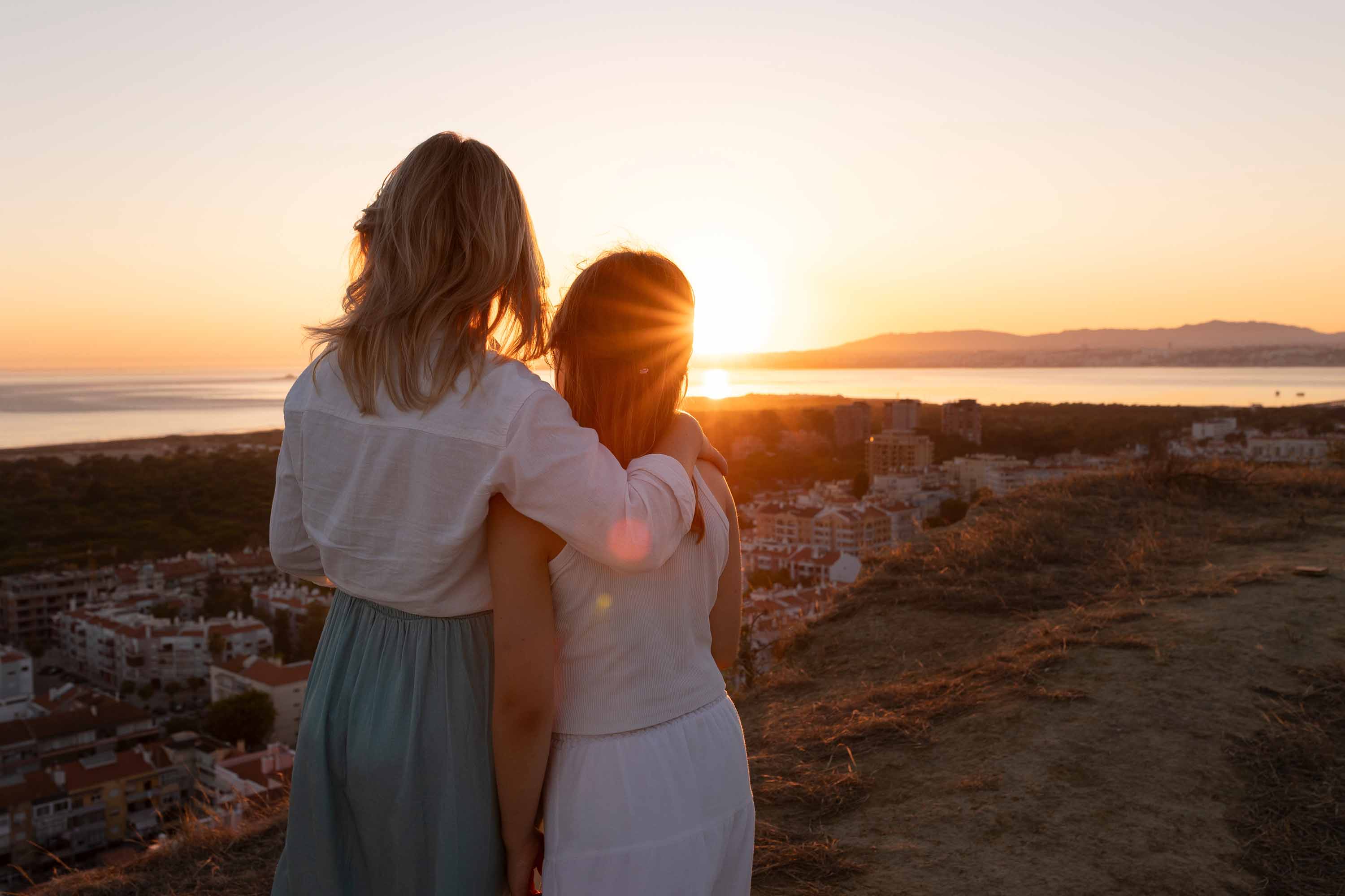 Mother and daughter enjoying the sunset over the sea in Portugal