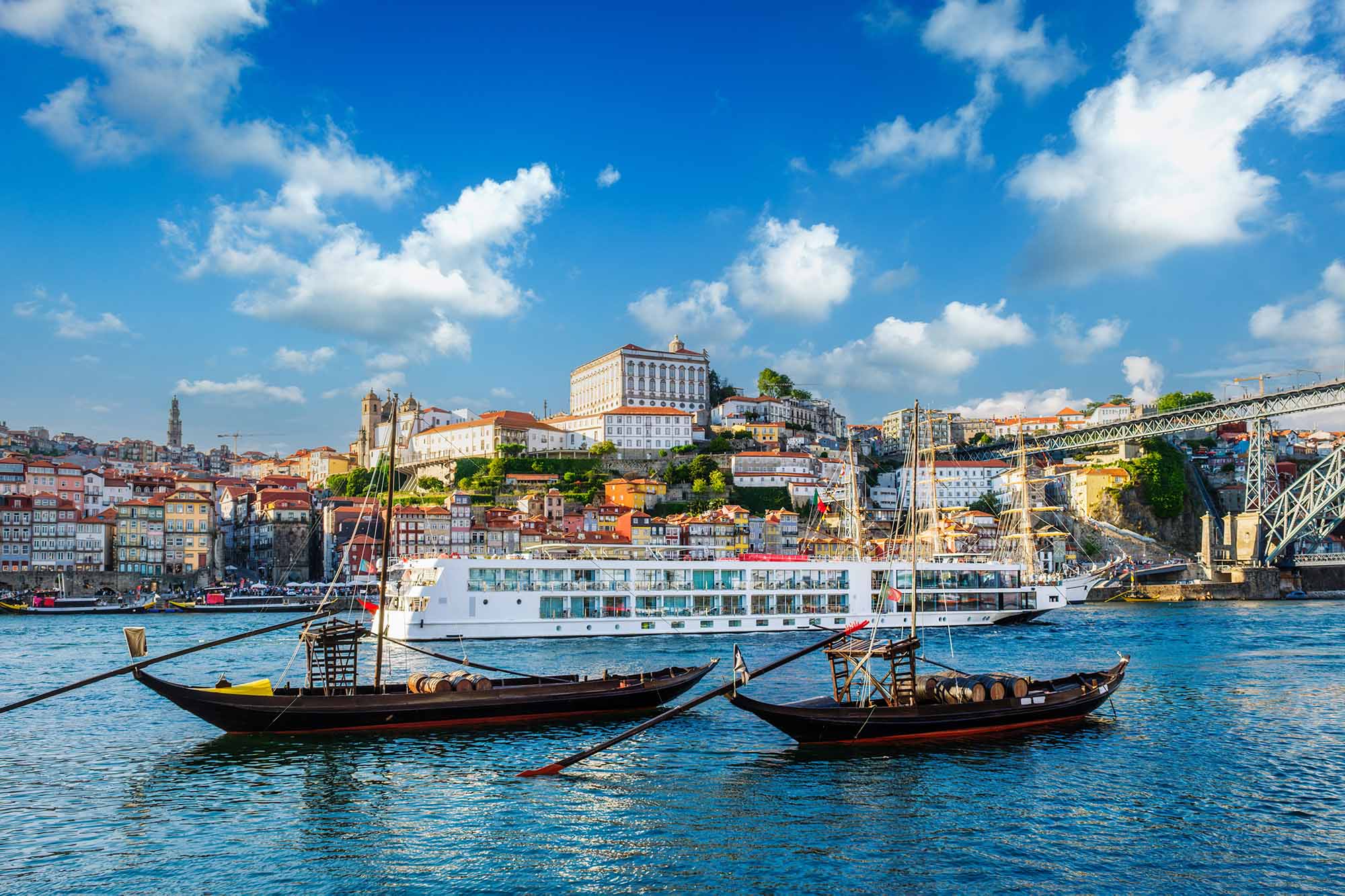 View of Porto city and Douro river with traditional boats with port wine barrels and sailing ship from famous tourist viewpoint
