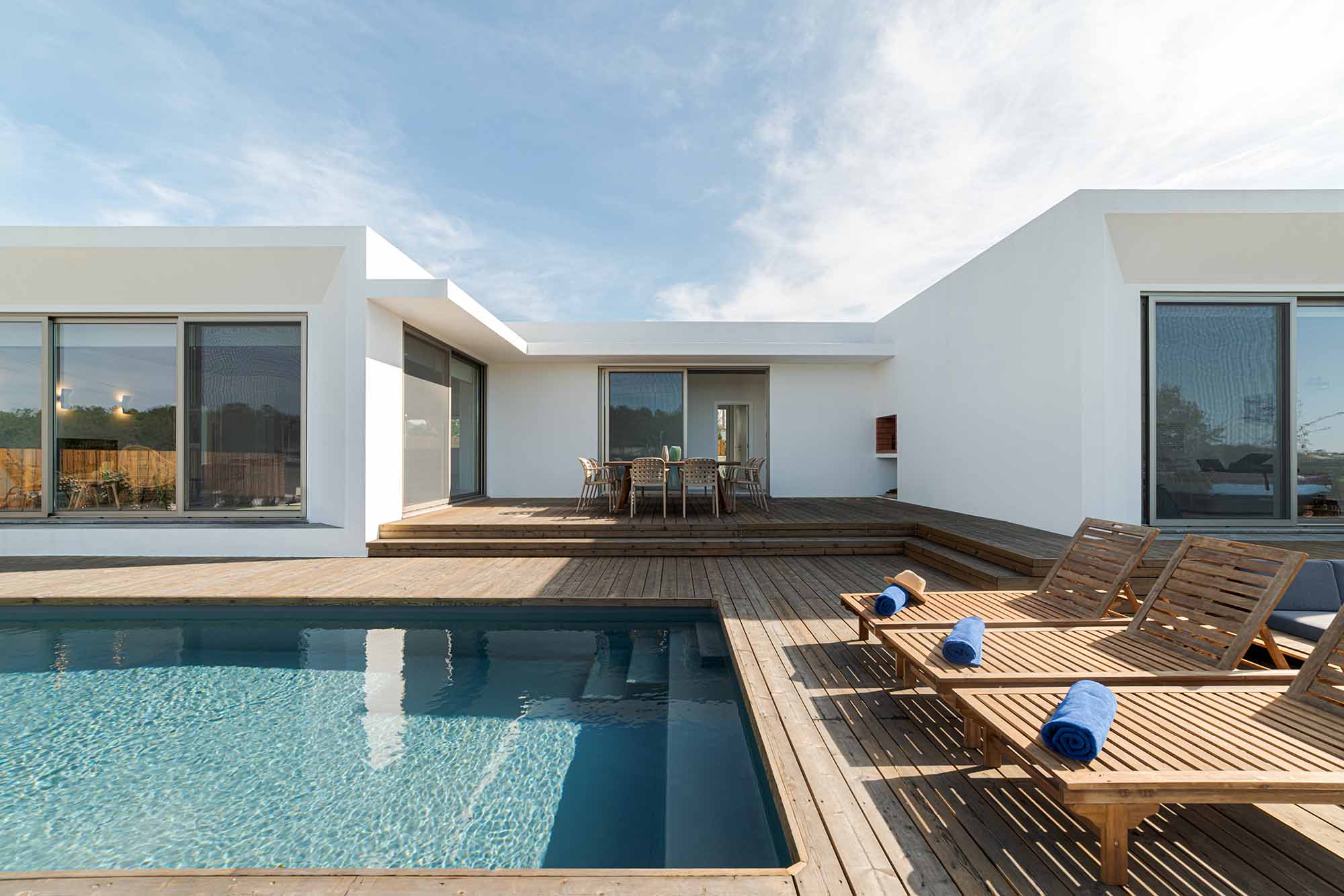 Wooden lounge chairs in modern villa pool and deck in Portugal