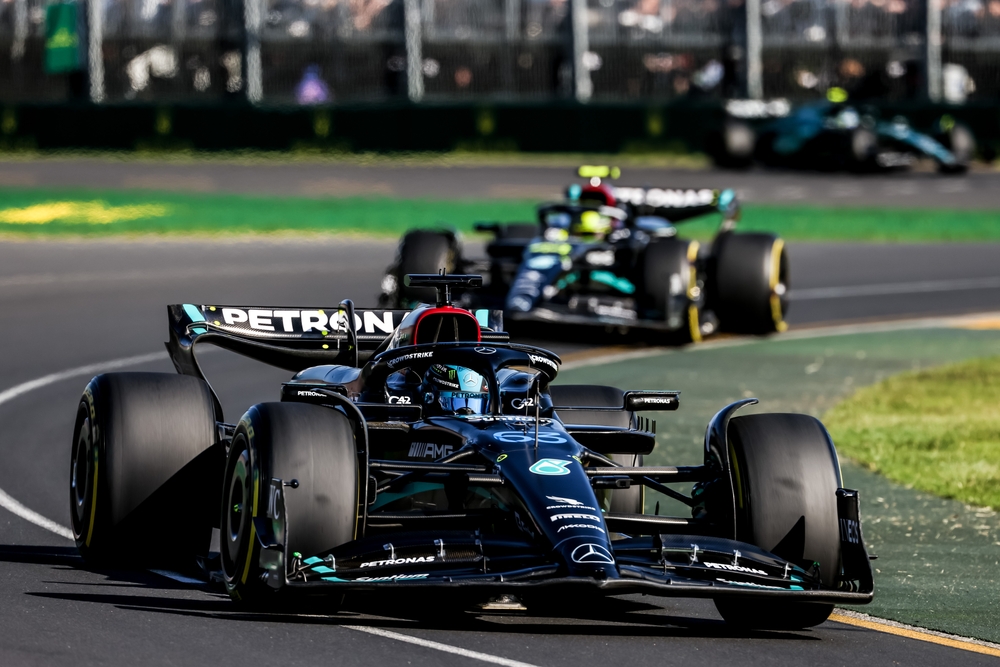 Formula 1 racing car leading another car around a turn on a professional track