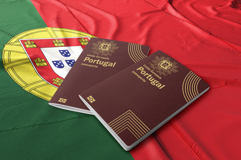 Two Portuguese passports lie side-by-side on a large, draped national flag of Portugal