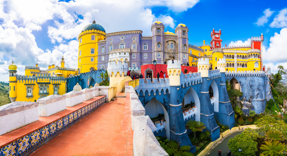 The colorful Pena Palace in Sintra Portugal under a bright blue sky with white clouds