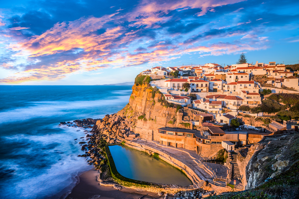 Coastal cliff-top village of Azenhas do Ma above a natural pool and the ocean at sunset