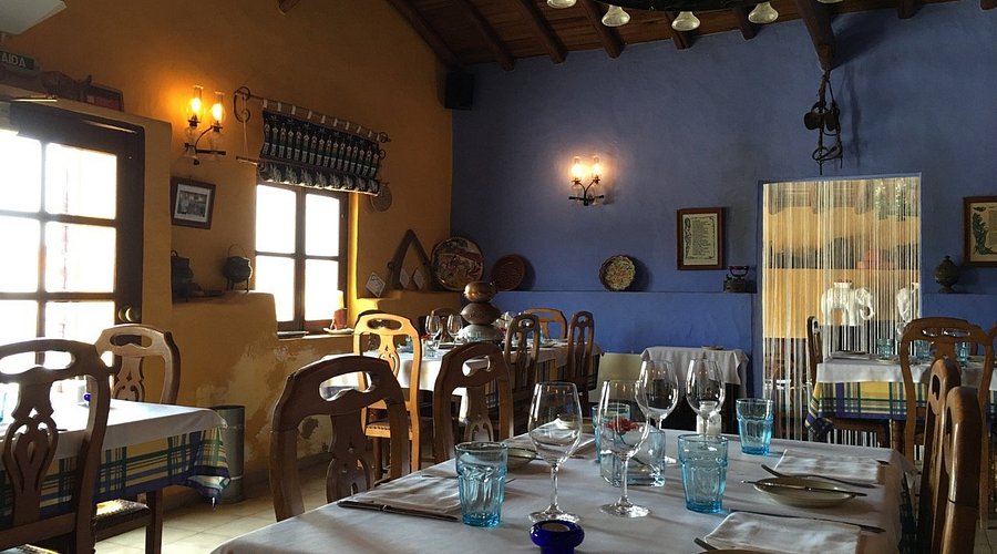 Rustic restaurant interior with yellow and blue walls and wooden chairs in a cozy setting