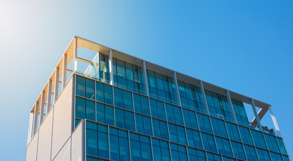 Modern glass office building facade under bright blue sky