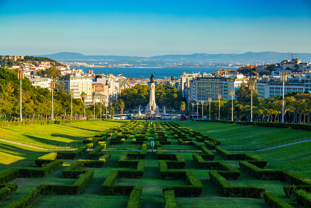 Eduardo VII Park in Lisbon with geometric hedges, cityscape, and view of the Tagus River