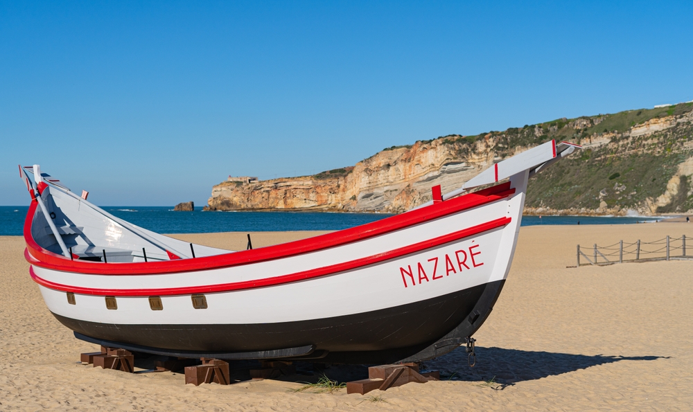 Traditional white and red fishing boat on a sandy beach under a clear blue sky