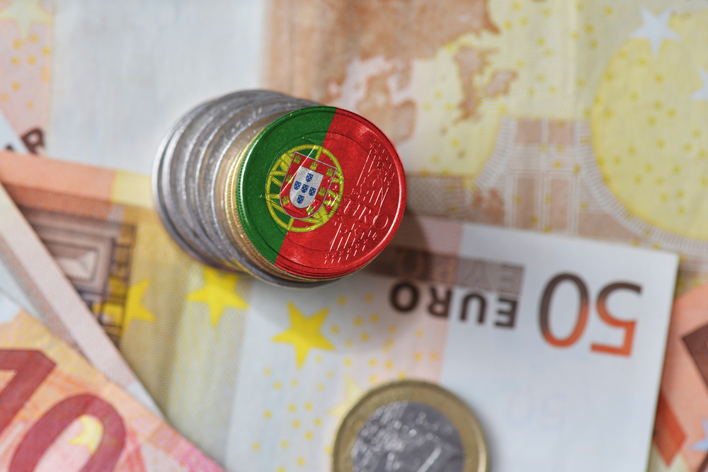 Portuguese flag-designed Euro coin on a stack of silver coins and 50 Euro banknotes