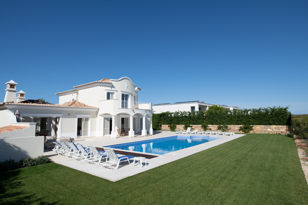 Modern luxury villa in Portugal with a large swimming pool, sun loungers and green lawn