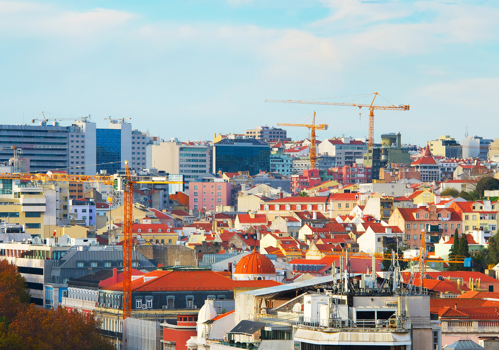 Lisbon city skyline with red roofs, modern buildings, and orange construction cranes