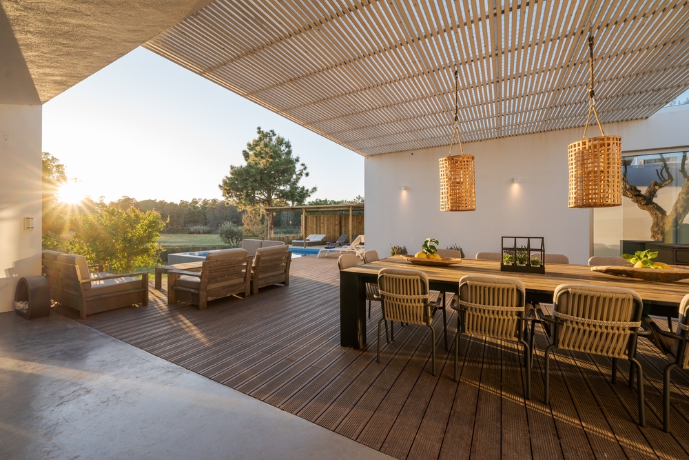Sunny villa patio with contemporary outdoor dining area pool view and wood deck