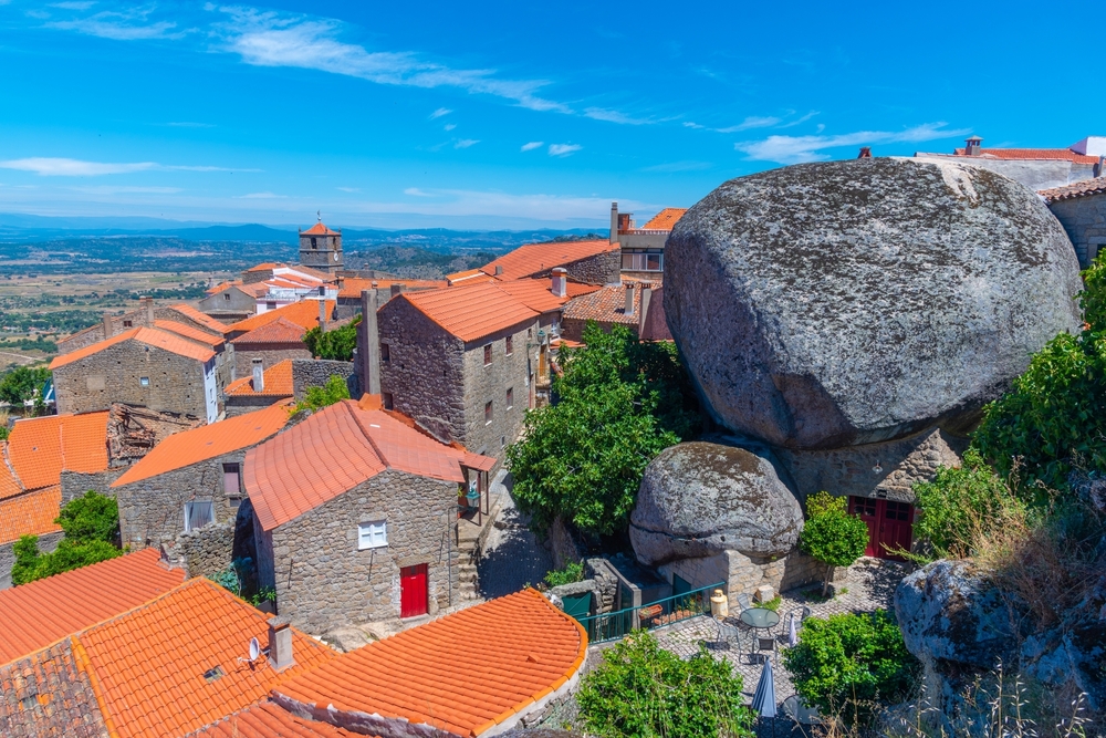 Monsanto village in Portugal with houses built among giant boulders under a blue sky