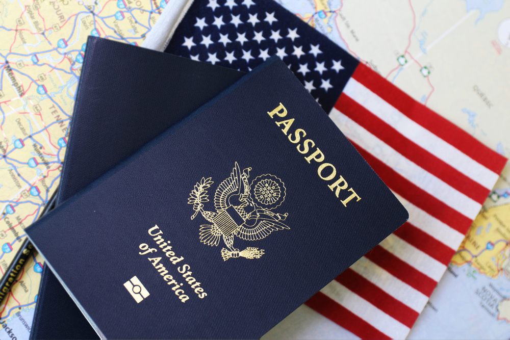 US passport and an American flag laying on map of the United States