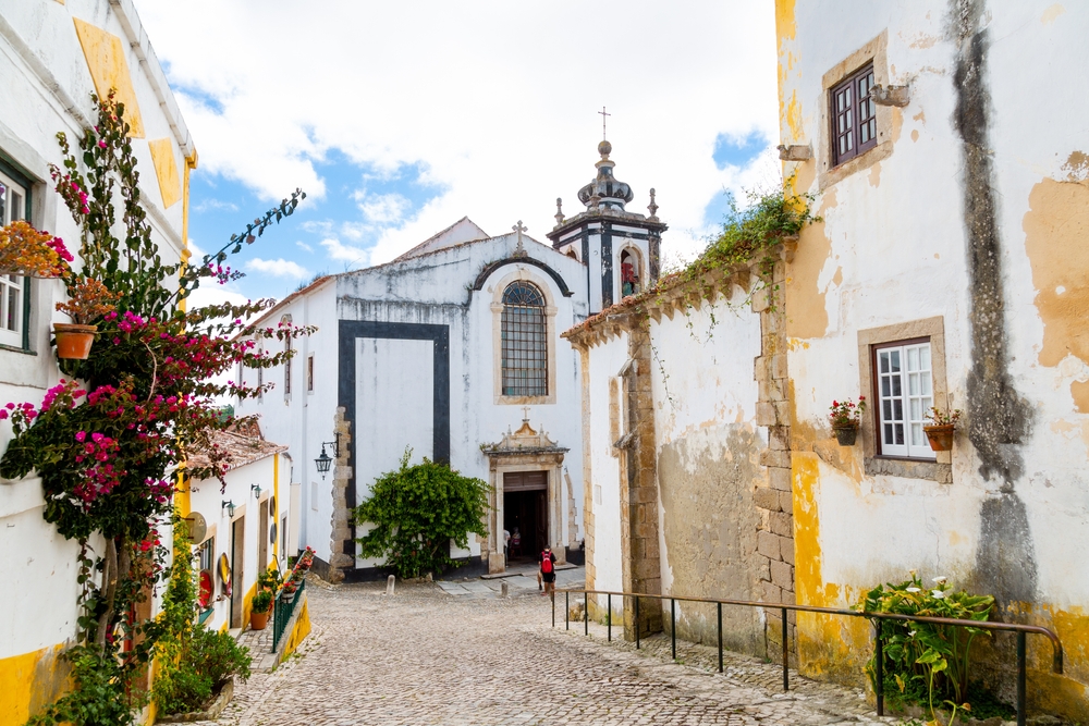 Beautiful street in Óbidos with Saint Peter church in the background