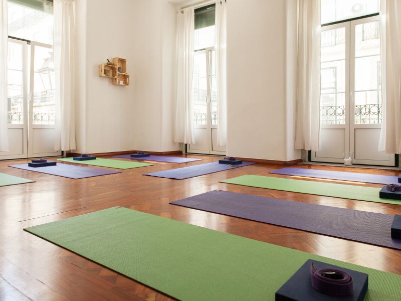 Indoor yoga studio with several colorful mats on a wooden floor and bright natural light