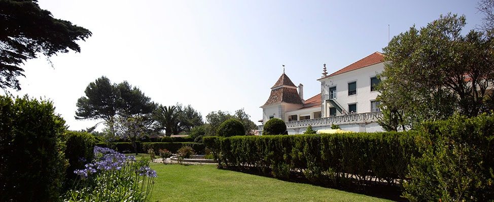 St Julian's School building with a red-tiled roof and garden in the sunshine