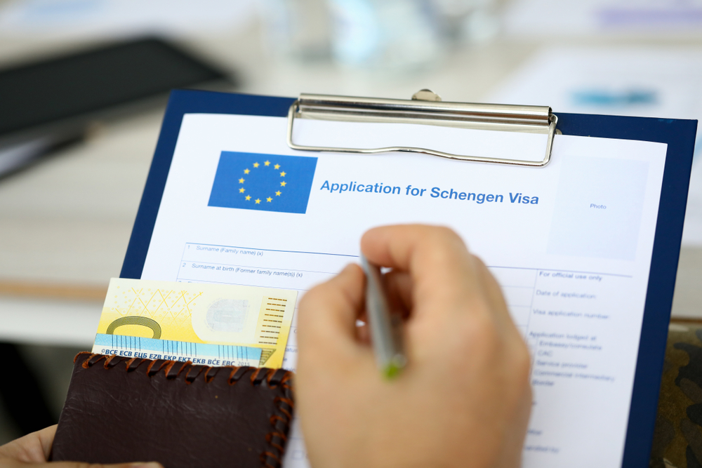 Close up of an Application for Schengen Visa on a clipboard with Euro banknotes in a wallet