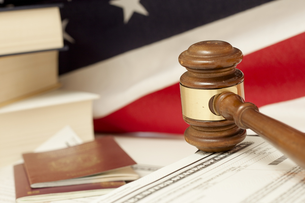 A wooden judge's gavel, US law papers, passports and books resting on an American flag