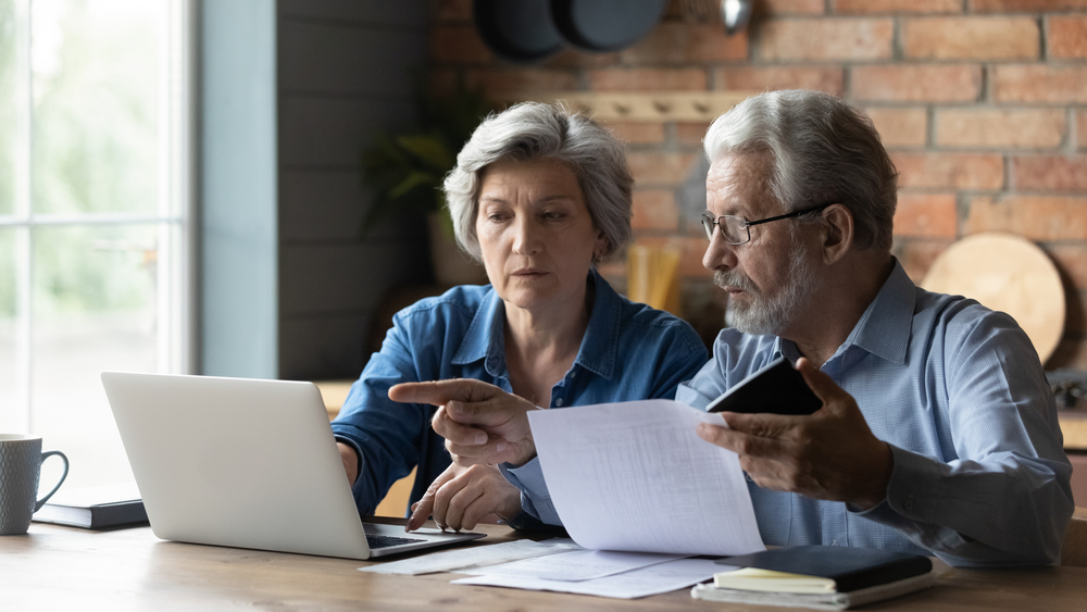 Older couple looking at open laptop discussing finances