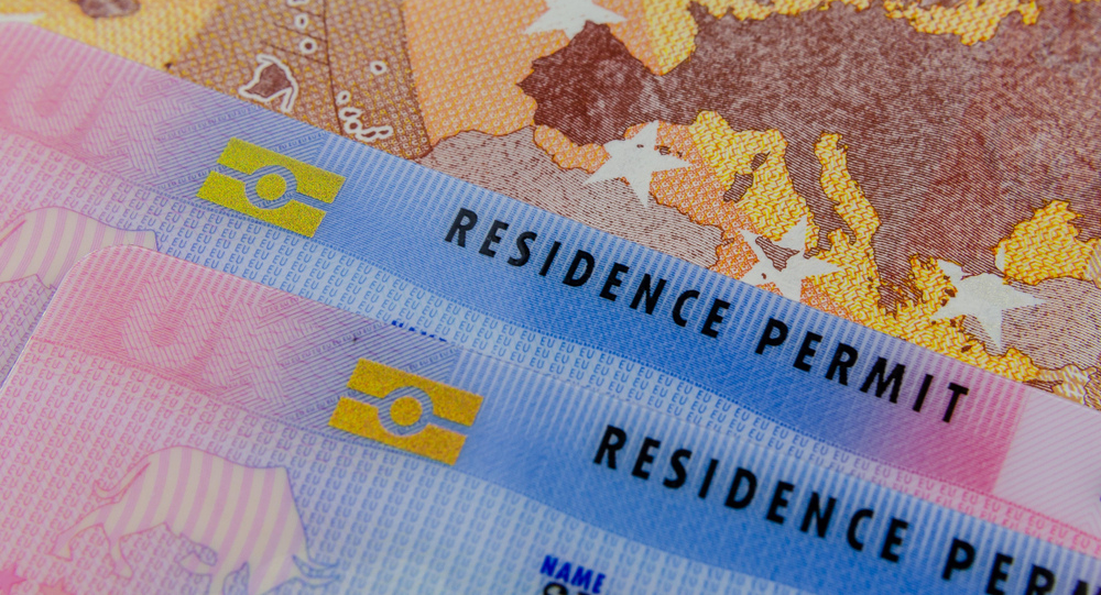 Close-up of multiple pink and blue European residence permit cards against a map of Europe