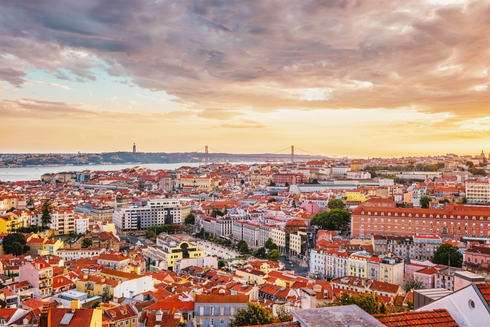 Lisbon city view with orange rooftops and the 25 de Abril Bridge at sunset