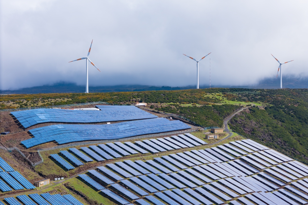Solar panels and wind turbines on a green mountain area