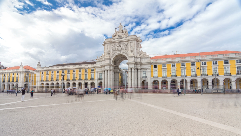 The Rua Augusta Arch in Lisbon, Portugal, stands prominently under a bright, cloudy sky