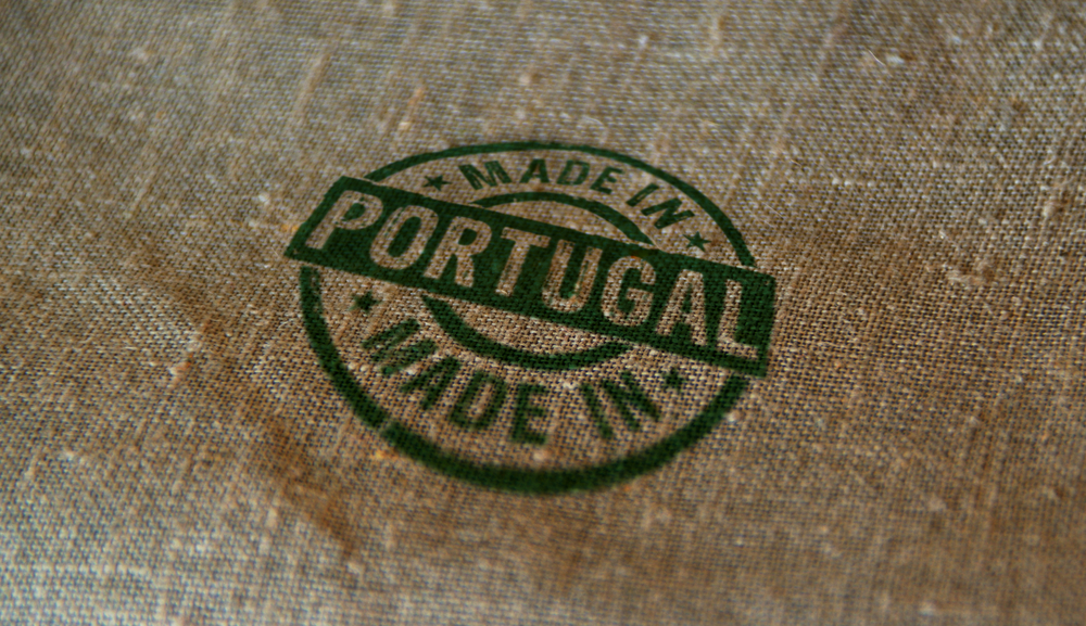 A green circular 'Made in Portugal' stamp printed on a textured burlap fabric