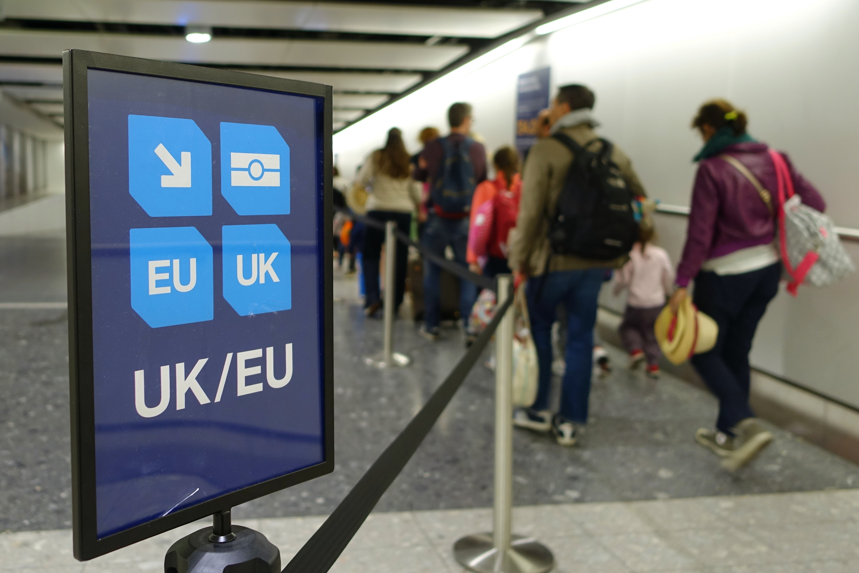 Queue at border control with UK/EU passport sign, highlighting post-Brexit travel and immigration process