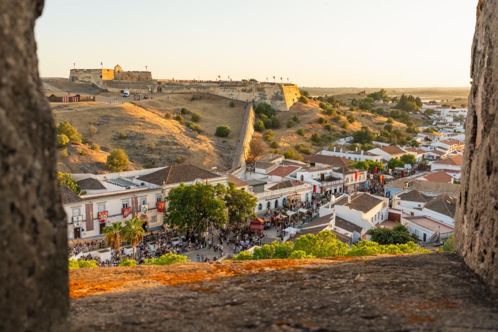 Colorful town square and rooftops in Castro Marim seen through stone-framed window