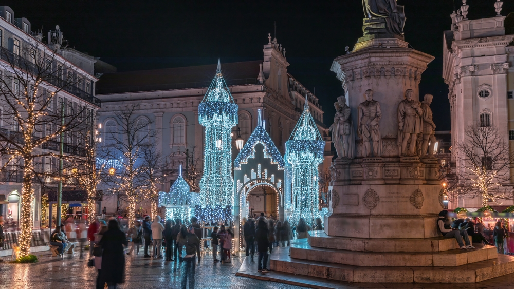 People walking around the Christmas lights and historic architecture at Luis de Camoes Square in Lisbon