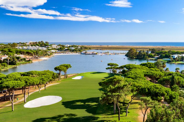Lush green golf course fairway and bunkers by a coastal lagoon and the ocean