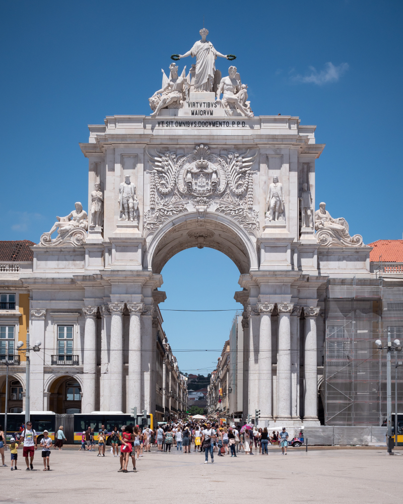 The historic Arco da Rua Augusta triumphal arch in Lisbon's Praça do Comércio under a clear blue sky
