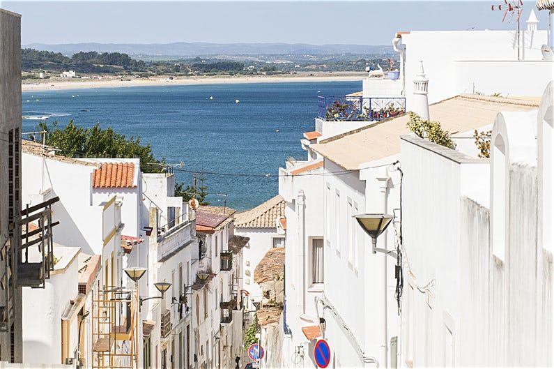 White-walled buildings on a steep street overlooking a scenic coastal bay