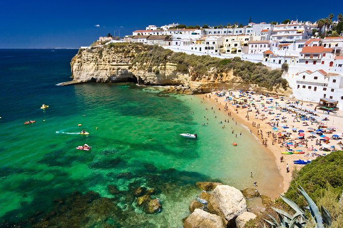 Crowded Carvoeiro beach in Portugal with turquoise water and cliffside buildings