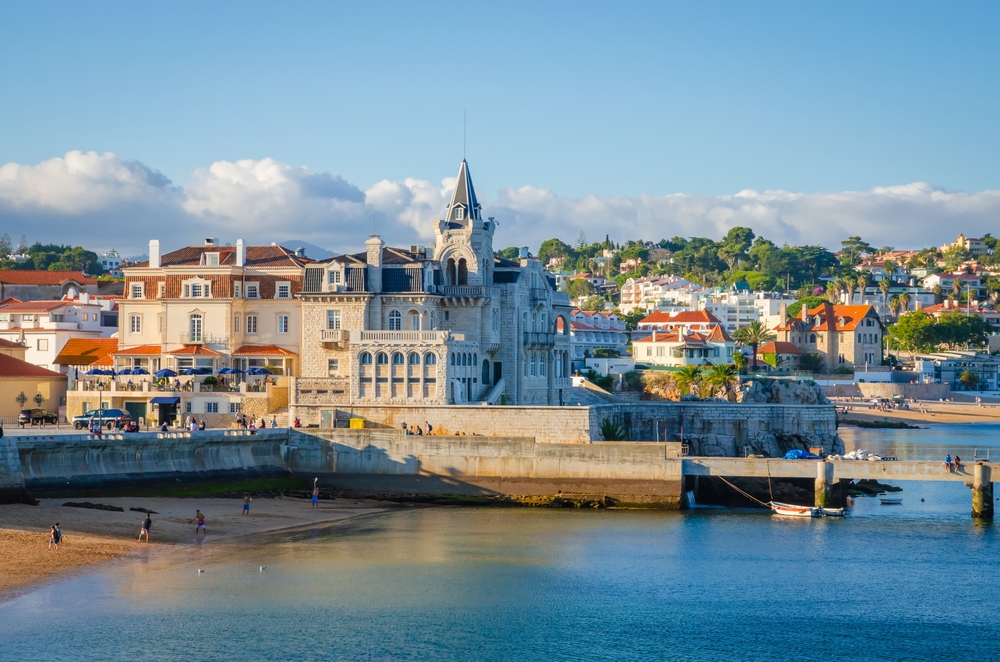 Historic coastal palace building overlooking a sandy beach and blue water in Cascais