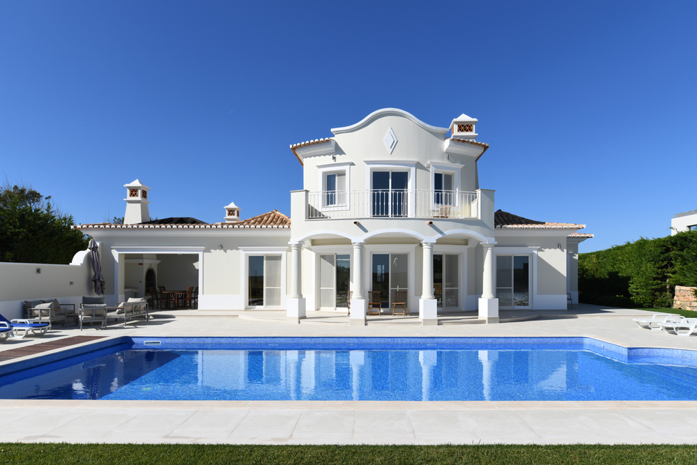 Modern luxury white villa with a blue swimming pool and outdoor lounge area in Portugal