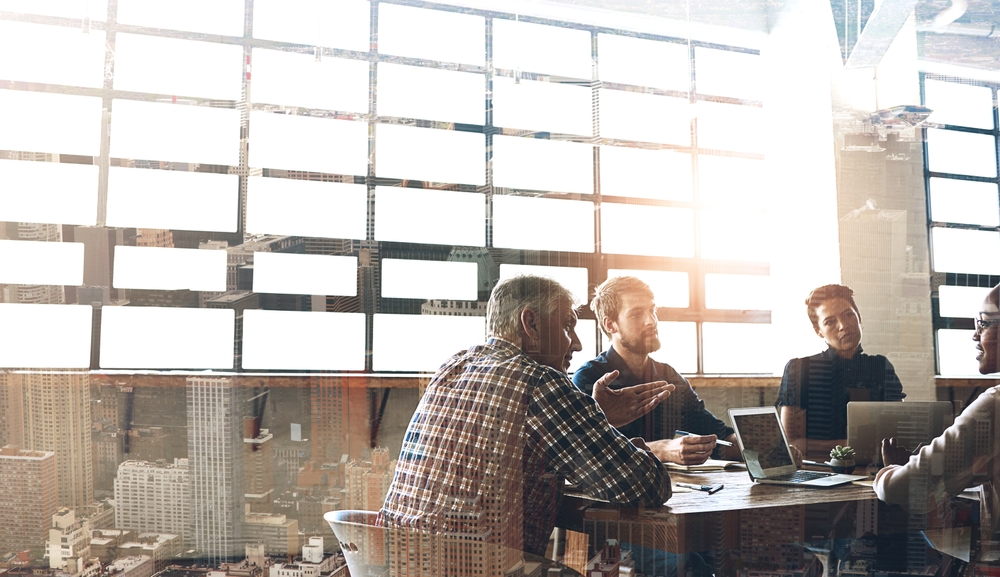 Professionals in a meeting and a city skyline through large windows